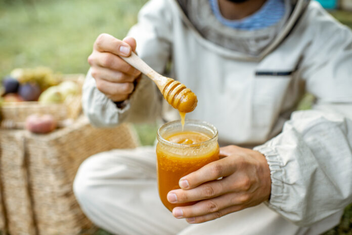 Beekeeper,Tasting,Honey,On,The,Apiary,Outdoors,,Close-up,View