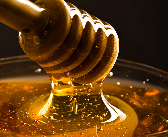 Isolated,Honey,Dropping,In,A,Jar,On,A,Black,Background