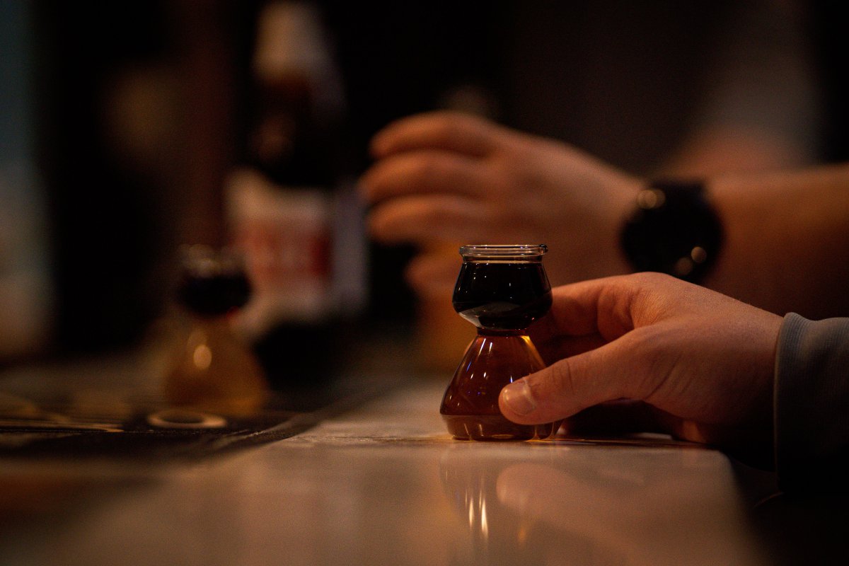 a-close-up-of-a-person-holding-a-small-glass-of-dark-liquor--26630774